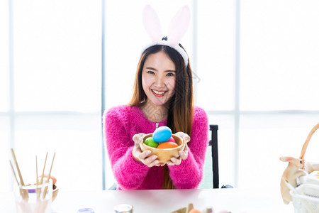 童年白种人抓住复活节的概念欢乐亚洲年轻女手展拿着一个篮子盛满多彩的复活节鸡蛋在白色房间背景图片