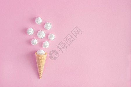 粉彩薄饼冰淇淋甜筒粉红背景上散落的白扭曲蛋时尚锥体图片