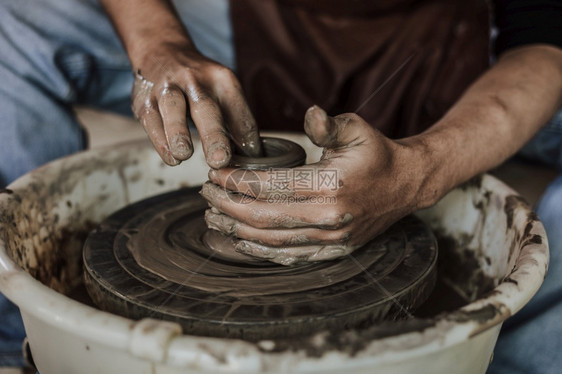 工艺泥术家在陶器车轮上工作的匠手掌选择焦点图片