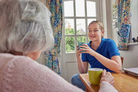 人们在厨房与单身年长妇女一起喝杯茶的家庭帮手关心在室内图片
