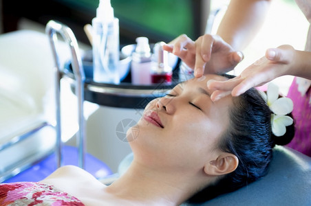 一位美丽的亚洲女躺下给员工清洗皮肤施用润湿剂脸上的皮肤护施用奶油铺设成熟治疗图片
