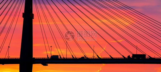 互换卡车拖和小驾驶在黄昏穿过悬吊桥背景为Silhouette的戏剧天空暂停抽象的图片