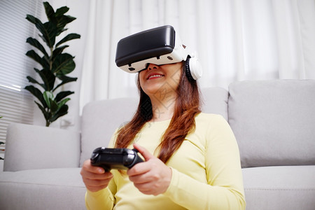 人们在客厅装着虚拟现实眼镜玩电游戏的年轻女青风镜乐趣图片