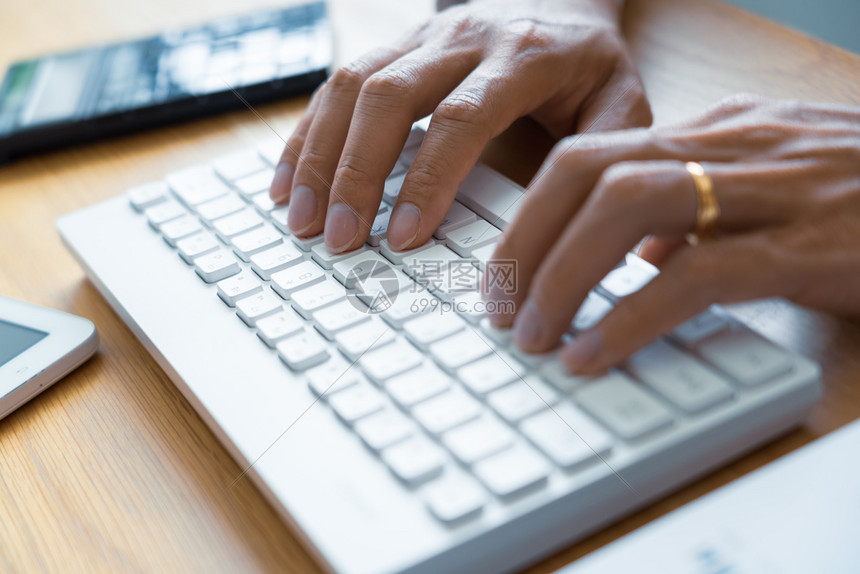 通过键盘打字在工作场所计算座位表和办公室工具上作撰写电子邮件交流在线概念等将男手放在键盘上贴近女在职的人们图片