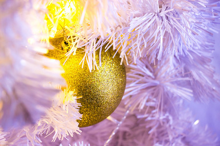 十二月金的关闭白色圣诞树配有金色的bouble吊挂装饰和bokeh模糊图片