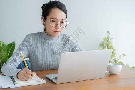 沟通女身戴眼镜的亚洲妇女正在家庭办公室使用笔记本电脑在智能技术设备上工作的年轻可爱小学生铅笔图片