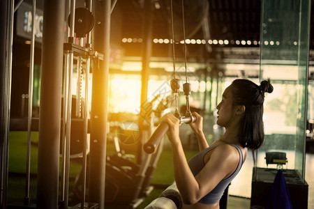 手臂健美运动员权重在健身房通过有线机模拟器运动和健康概念在身锻炼中的肌肉适合身体妇女图片