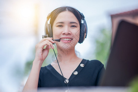接触电话营销微笑在家庭呼叫中心服务处工作的亚洲妇女咨询支助商业工作新常态女在家庭呼叫中心服务处工作图片