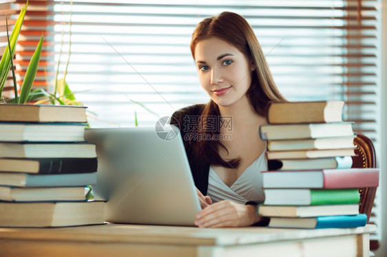 坐在书本中间笔记电脑上工作的漂亮女学生肖像有趣年轻娱乐图片