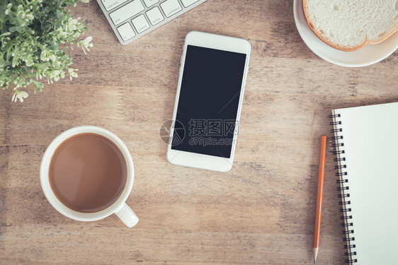 平坦的现代电话办公桌顶端有笔记本咖啡杯膝上型智能手机和铅笔图片