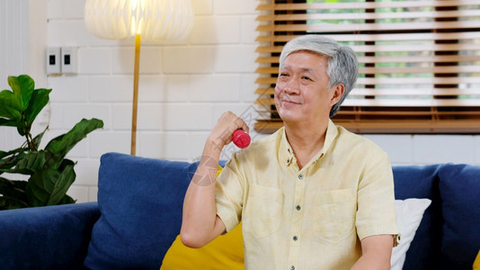 日本人们有意识的老年男子在家锻炼快乐老年男子为健身而举哑铃康退休老人在训练体重时适合身力健康福利概念的体育健康退休老人图片