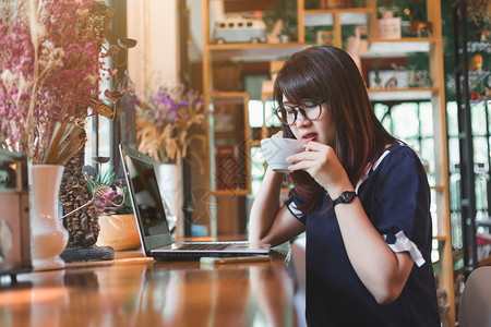 从事笔记本电脑工作的亚洲女商人在咖啡店里像背景一样作笔记女士在职的杯子图片