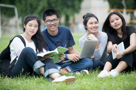 亚洲学生们在草坪上一起讨论问题图片