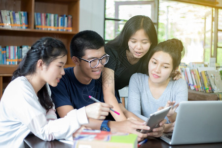 亚洲学生们一起在书架前讨论问题图片