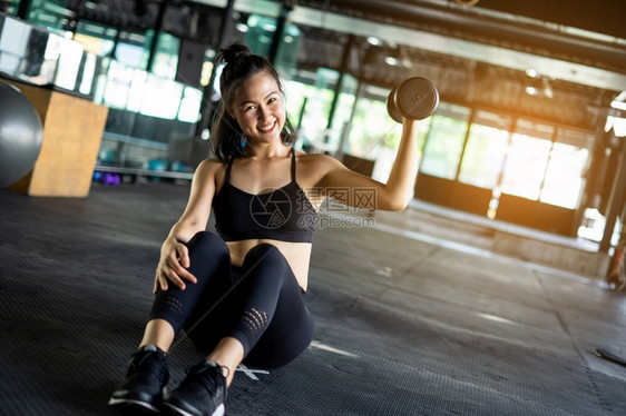 有运动功能的美丽女运动员使用模糊背景健康生活和体育锻练设备及概念的哑铃轻重训练设备并带有复制空间运动场肌肉发达活力保持图片