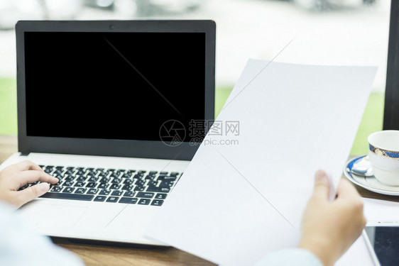 在职的咖啡店像背景一样持有空白文件的手提笔记本电脑和手袋女商业工作者的近身数字屏幕图片