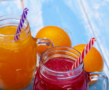食物异国情调两套玻璃容器橙汁和葡萄油蓝色桌上有吸管和稻草一种图片