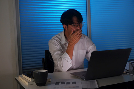 电脑坐着真实的年青亚洲商人深夜加班工作图片