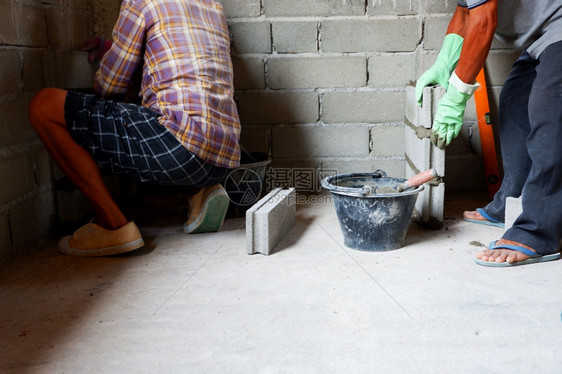 手技能安全人砖工正在为块水泥墙建造新房屋而工作图片