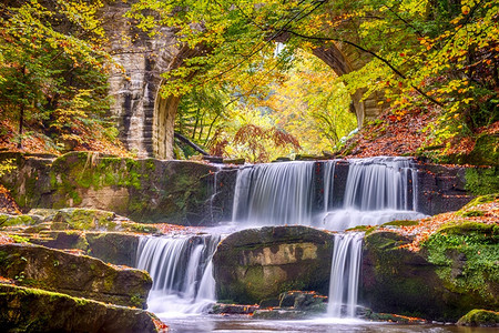 岩石树叶户外秋天在阳光明媚的森林中古老石头桥小河和几个天然瀑布在一座石桥的森林和拱门中瀑布图片