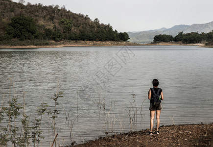 一位年轻的亚洲女站立并欣赏湖岸景色的背影是山脉假日旅游概念休息和享受生活方式焦点和模糊常设热带一种图片