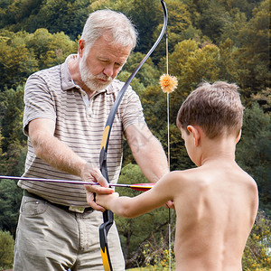 年长男人教小孩怎么把箭放弓中瞄准学习图片