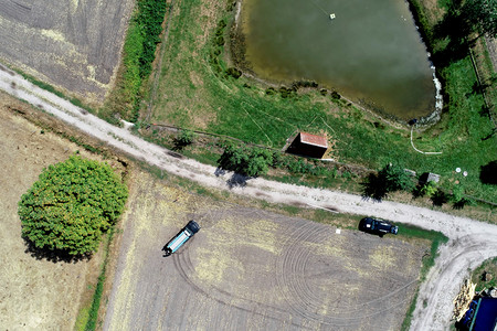 收成稻草获垂直空中观察在采伐田和草地旁边的一条道路上方有一个小马匹在池塘前进行捕捞图片