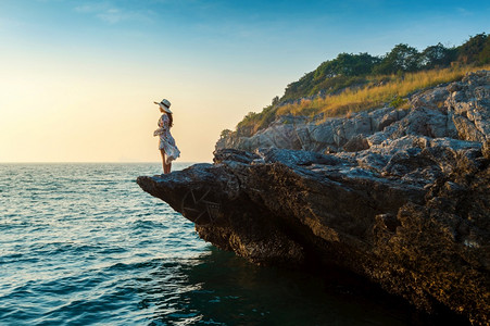 顶峰山景观站在岩石顶端的年轻女子看着海边和西昌岛的日落图片
