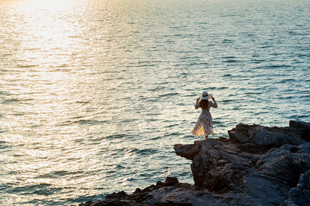 成功游客站在岩石顶端的年轻女子看着海边和西昌岛的日落站立图片