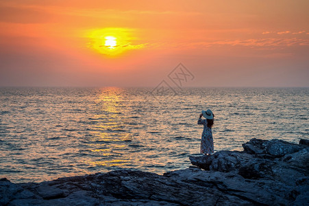 海滩常站在岩石顶端的年轻女子看着海边和西昌岛的日落自然图片