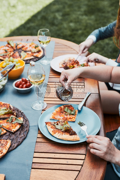 家人和朋友在庭花园的夏季野餐户外晚期间用比萨沙拉水果和喝白葡萄酒在家庭花园的夏季野餐户外晚期间喝白葡萄酒后院盘子食物图片