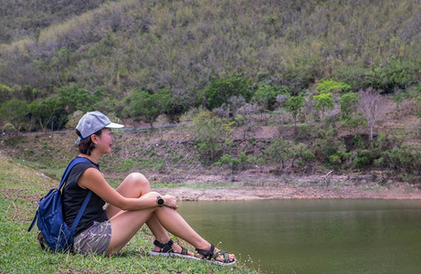 河外部在湖岸边坐和享受美好景色平时刻的年轻青女侧面观其背景为假日旅行概念休息和享受生活方式选择重点等山脉分布在上一种图片