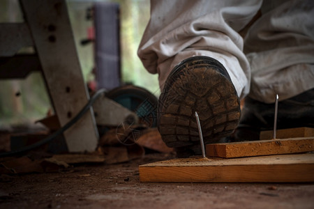 工匠在建筑区用安全鞋踩板木上钉子的工人齿轮踏步伐图片