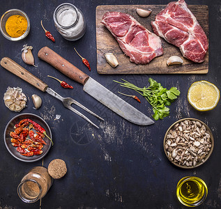 用刀和叉子在剪切板上用新鲜的原生猪肉牛排餐桌上用火辣红胡椒柠檬和黄油木制生锈背景牛腩腰部木制的图片