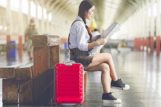 女在火车站旅行时亚洲孕妇坐在长椅上看和红色手提箱的皮Holiday旅行概念父母乘客图片