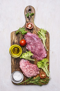 杂货店新鲜猪肉牛排配有沙拉番茄油和盐在木制生锈背景最接近的顶端观光板上饮食肌肉图片