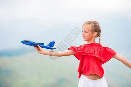 游戏客机顶峰在山上放暑假时带小飞机玩具的可爱女孩带着玩具飞机在山上握着玩具机的快乐小女孩图片
