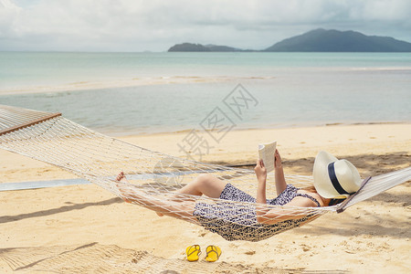 麦女在节假日暑自由时间阅读关于吊床上海滩的书籍休息躺着图片