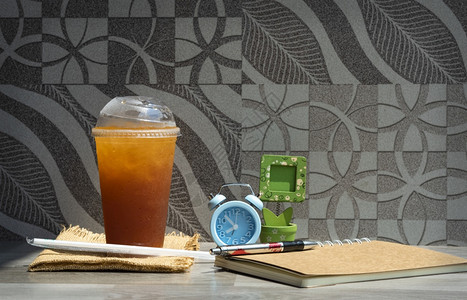 球饮料茶杯中新鲜的冰装有稻草笔记本蓝闹钟和桌边小木画框面壁装饰背景清新休闲活动概念警报图片