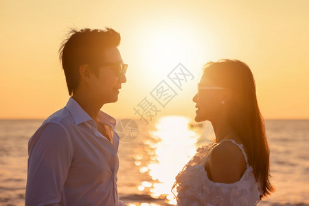 男人年轻快乐的亚洲夫妇在海滩上互相看对方浪漫旅行蜜月度假暑亚洲女和男在日落背景下手拥抱户外的亚裔男女孩保持图片