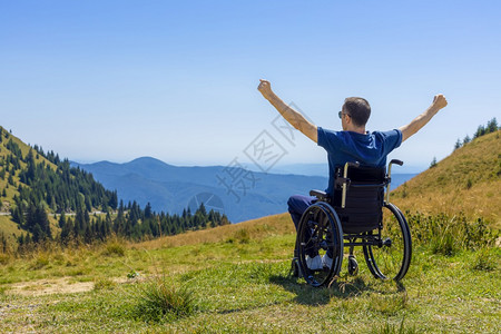 坐在轮椅上的年轻人在山上阳光明媚的一天享受新鲜空气夏天车轮活动图片