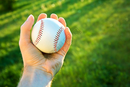 投球手牵对着绿色新鲜草地握着棒球圆形的播放器图片