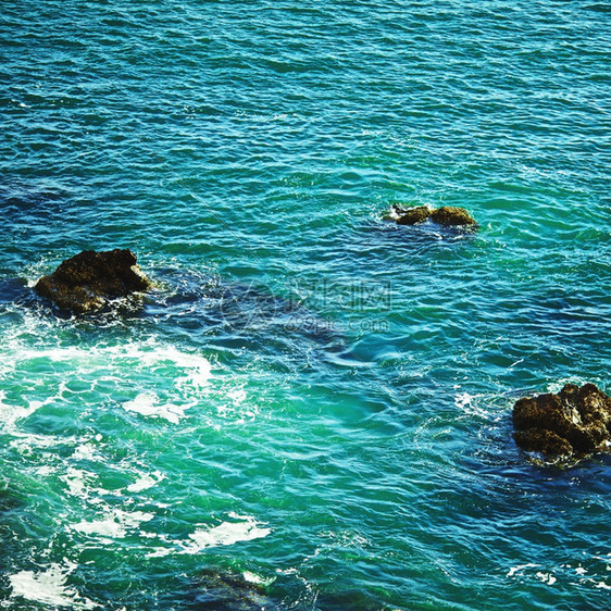 多岩石的在阳光明媚天气下在岩石海岸冲浪正方形照片图片