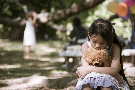 抱着玩具熊的孤单小女孩图片