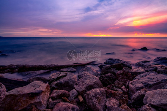 黄昏的石滩和平静海面紫色日落天空热带的海晚上天线黄金紫色和红的天空夏海景暑假旅行岩石海岸洋中的美人假期云戏剧图片