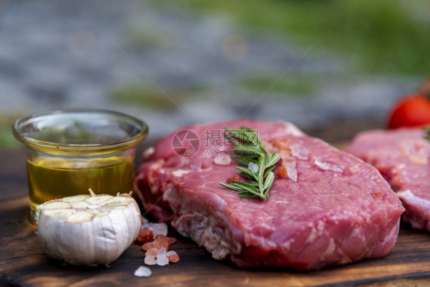 里脊肉煮熟的不在厨房木板餐桌背景上有迷迭香盐大蒜番茄黑辣椒橄榄油肉牛排和制品的木板上肉图片