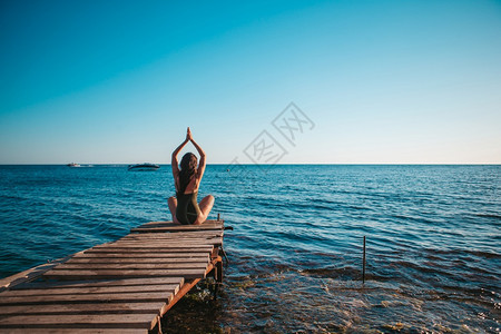 海浪合身运动年轻漂亮的女人在码头上练习瑜伽年轻漂亮的女人在海滩上练习瑜伽图片