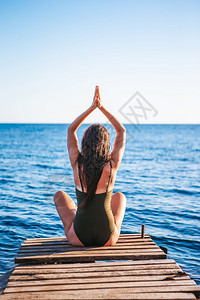 年轻漂亮的女人在码头上练习瑜伽年轻漂亮的女人在海滩上练习瑜伽户外摆姿势美丽的图片