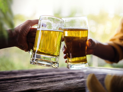 愉快茶点两个朋友在夏天的Balcony与眼镜和啤酒喝杯享受图片