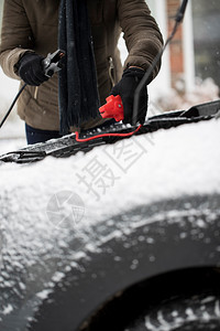 司机白雪皑车库天在汽电池上使用跳跃缆的妇女图片